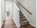 Inviting entryway with hardwood floors and carpeted stairs, leading to a bright kitchen in the background at 9142 Widden Way, Charlotte, NC 28269