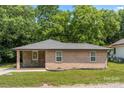 Single-story brick home with stone facade, covered porch, and well-maintained lawn, set against a lush green backdrop at 1116 S Juniper St, Kannapolis, NC 28081