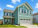 Inviting exterior featuring a two-car garage, covered porch, and light teal plank and shake siding at 133 Aspire Cir, Wingate, NC 28174