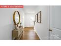 Inviting foyer featuring beautiful wood floors, console table with decor, mirror, and natural light at 1373 Zermatt Ct, Monroe, NC 28112