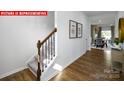 Bright hallway featuring wood floors, stairs with carpet and railing, with views into the dining and living area at 1373 Zermatt Ct, Monroe, NC 28112