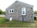 Stone house with a basement door and a glimpse of the spacious yard at 209 14Th Se Ave, Hickory, NC 28602