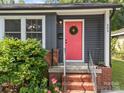 Close-up of a vibrant red front door with wreath, set against gray siding and brick steps at 309 Ackert Ave, Salisbury, NC 28144