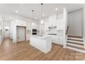Spacious kitchen with a central island, white cabinets, and stainless steel appliances, complemented by hardwood floors at 3124 Beacon Heights Rd, Indian Land, SC 29707