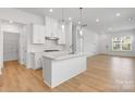 Bright, modern kitchen featuring a center island, white cabinets, stainless steel appliances, and hardwood floors at 3124 Beacon Heights Rd, Indian Land, SC 29707