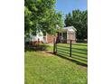 View of the home's brick and siding exterior with a black metal fence and charming screened-in front porch at 490 S Moose Rd, Mount Pleasant, NC 28124