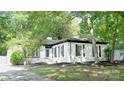 Charming white brick home with black shutters and trim, set amidst lush trees and meticulous landscaping at 6128 Coatbridge Ln, Charlotte, NC 28212