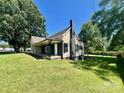 Exterior of a charming single-story home featuring a covered porch, chimney, and lush green lawn at 614 E Main Ave, Taylorsville, NC 28681