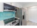 Modern kitchen featuring stainless steel appliances, turquoise backsplash, and white cabinets at 712 Mallard Head Ln, Mooresville, NC 28117