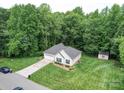Aerial view of a home with a spacious yard, shed, driveway, and surrounded by mature trees at 727 Cove Rd, Gastonia, NC 28052