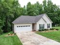 Inviting home with attached garage, well-kept lawn, and a long driveway, surrounded by lush trees at 727 Cove Rd, Gastonia, NC 28052