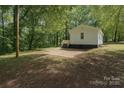 View of backyard with a small white house and concrete patio, surrounded by mature trees at 905 Gantt St, Kings Mountain, NC 28086