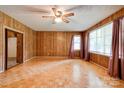 Bright living room featuring wood-paneled walls and parquet flooring at 105 Hopewell Church Rd, Shelby, NC 28152