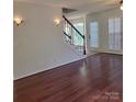 Spacious living room showcasing hardwood floors, staircase, decorative sconces and natural light at 13039 Peacock Ln, Charlotte, NC 28215