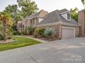 Elegant brick home showing the garage and driveway with a landscaped front yard and mature plantings at 15708 Eagleview Dr, Charlotte, NC 28278