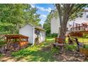 Secluded backyard with a storage shed, wood storage, a bench, mature trees, and well-maintained lawn at 167 Foxtail Dr, Mooresville, NC 28117