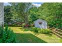Private backyard featuring a storage shed, wooden fence, bench, mature trees, and well-manicured lawn at 167 Foxtail Dr, Mooresville, NC 28117