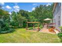 Expansive backyard featuring a deck, patio, garden beds, a wooden pergola, and mature trees at 167 Foxtail Dr, Mooresville, NC 28117