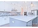 Bright kitchen with white cabinets, stainless steel appliances, and gray backsplash tiles at 4178 Millstream Rd, Denver, NC 28037