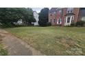 View of the large lawn leading up to a red brick home with tidy landscaping at 4227 Kiser Woods Sw Dr, Concord, NC 28025