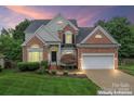 Elegant brick home with manicured landscaping, a two-car garage, and a welcoming front yard at sunset at 6632 Hawksnest Dr, Charlotte, NC 28269