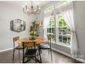 Cozy dining area with a wooden table, modern chandelier, and large windows that offer bright, natural lighting at 7881 Mariners Pointe Cir, Denver, NC 28037