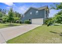 Long driveway leading to a two-car garage and backyard basketball hoop, surrounded by well-maintained lawn at 8340 Breton Way, Harrisburg, NC 28075