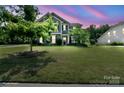 Charming two-story home boasts lush green lawn and mature trees in a well-maintained front yard at 8340 Breton Way, Harrisburg, NC 28075
