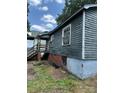 Side view of the house with weathered wood siding and a brick foundation, showing signs of repair at 839 S Chester St, Gastonia, NC 28052