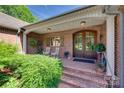 Inviting front porch featuring brick steps, wooden rocking chairs, and an elegant arched wooden front door at 103 3Rd Sw St, Catawba, NC 28609