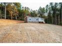 Charming home featuring a gravel driveway and lush green backdrop of tall trees at 122 River Ridge Ln, Hickory, NC 28601
