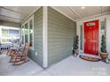 Charming front porch with a vibrant red door and inviting rocking chairs at 15018 Marymont Ave, Huntersville, NC 28078