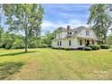 Inviting white farmhouse with a lush green lawn and mature trees at 604 Ferguson Ridge Rd, Gastonia, NC 28052