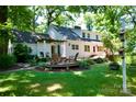A lush backyard features mature trees, a pergola, a deck, and outdoor seating at 613 E Ridge St, Kings Mountain, NC 28086