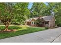 Beautiful brick home with mature trees and a long concrete driveway at 10311 Windtree Ln, Charlotte, NC 28215