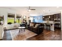 Open-concept living room with hardwood floors, large windows, and view into kitchen with granite countertops at 132 Hillston Ln, Mooresville, NC 28115