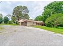 View of the building's exterior featuring a covered side porch and ample parking space, surrounded by lush greenery at 1529 Stony Point Rd, Shelby, NC 28150