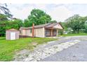 A single-story home with light siding, a covered porch and a brick chimney, nestled among mature trees at 1529 Stony Point Rd, Shelby, NC 28150
