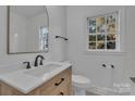 Bright bathroom featuring a wood vanity with white countertop, neutral tile, and modern fixtures at 4315 Gibbon Rd, Charlotte, NC 28269