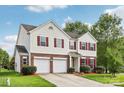 Charming two-story home featuring a brick and vinyl facade, red shutters, a well-manicured lawn and a two car garage at 5002 Abode Lily Ln, Charlotte, NC 28227