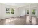 Bright living room with large windows, wood floors and decorative columns at 5002 Abode Lily Ln, Charlotte, NC 28227