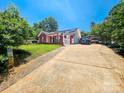 View of the house and driveway featuring a carport, green lawn, and mature landscaping at 501 N Johnson St, Monroe, NC 28112