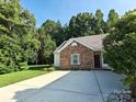 Single-story home with a long driveway and brick exterior accents in a wooded setting at 509 Settlers Grove Ln, Salisbury, NC 28146