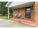 Inviting front porch with brick flooring, seating, and a charming entrance to the home at 6206 Clearwater Dr, Indian Trail, NC 28079