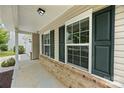 Exterior showcasing a covered front porch with brick accents and decorative green shutters at 8400 Empress Ct, Charlotte, NC 28227
