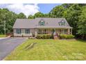 Inviting single-Gathering home featuring a spacious lawn, covered porch, green shutters, and a paved driveway at 8632 Island Point Rd, Sherrills Ford, NC 28673