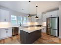Bright kitchen featuring white cabinets, stainless steel appliances, a kitchen island with light countertops and modern pendant lighting at 1724 Dallas Ave, Charlotte, NC 28205