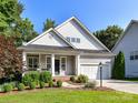 Charming home featuring a covered porch, attached garage, manicured landscaping and mature trees at 2215 Henery Tuckers Ct, Charlotte, NC 28270