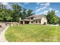 Expansive backyard featuring a large lawn, outdoor patio with fireplace, and lush landscaping at 4005 Capullo Ct, Matthews, NC 28104