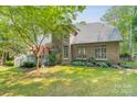 Large backyard with a wooden deck, green lawn, mature trees, and a black fence at 4075 Crepe Ridge Dr, Denver, NC 28037